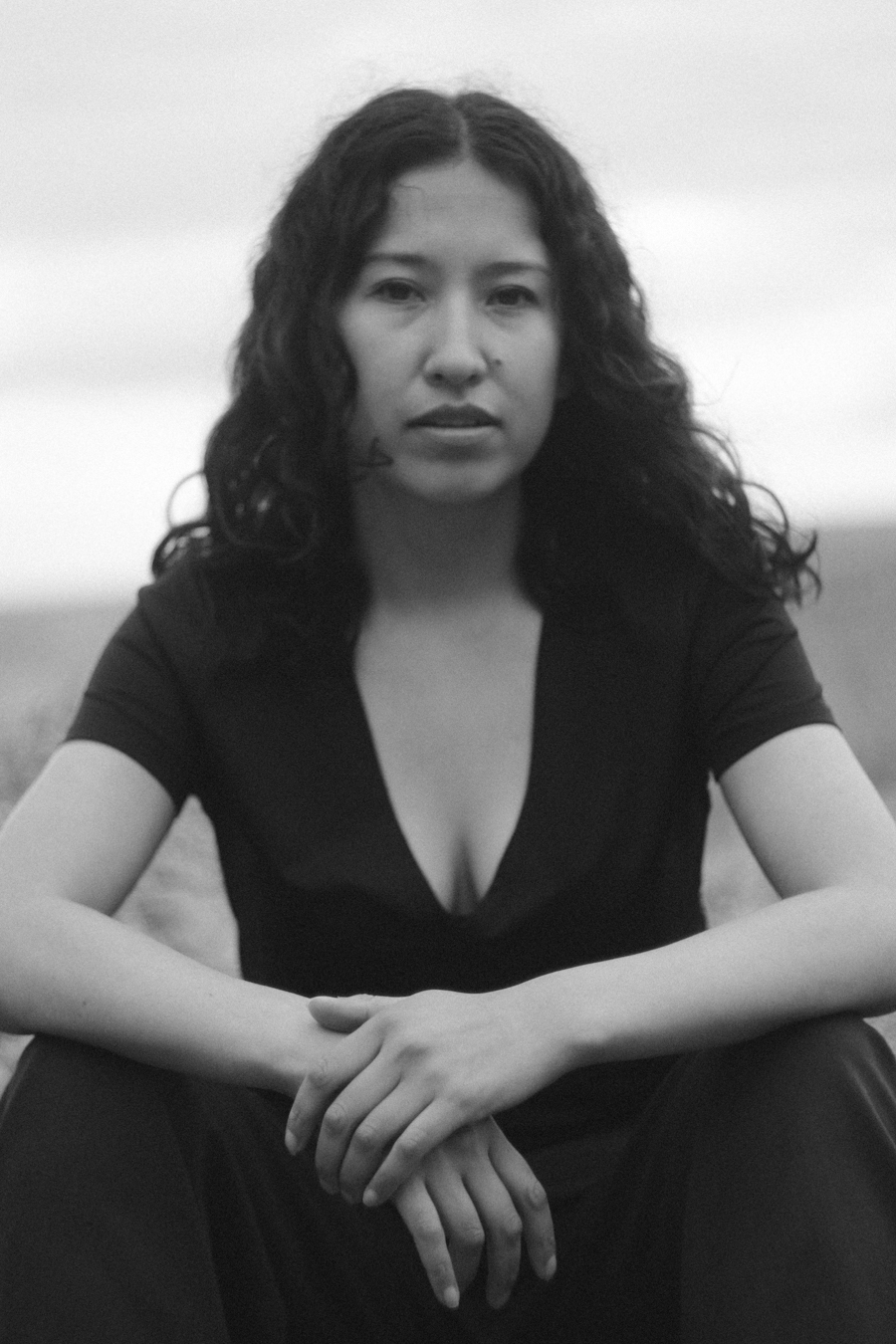 Retrato sentado en blanco y negro de Sasha Salaverry con las manos juntas.