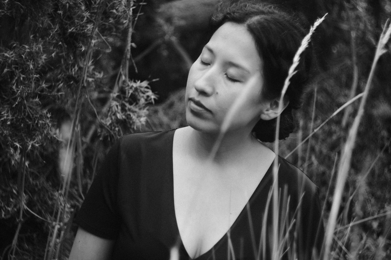 Retrato en blanco y negro de Sasha Salaverry entre pastos altos.